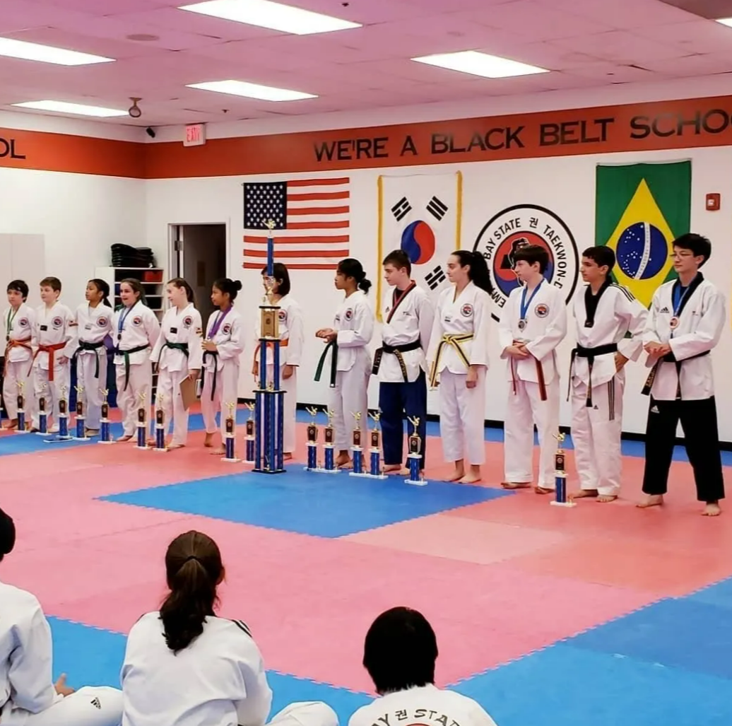 A woman in a taekwondo uniform is doing a kick on a red background