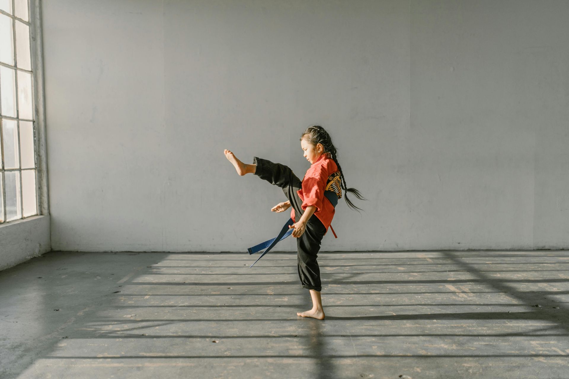 A young girl is practicing karate in an empty room.