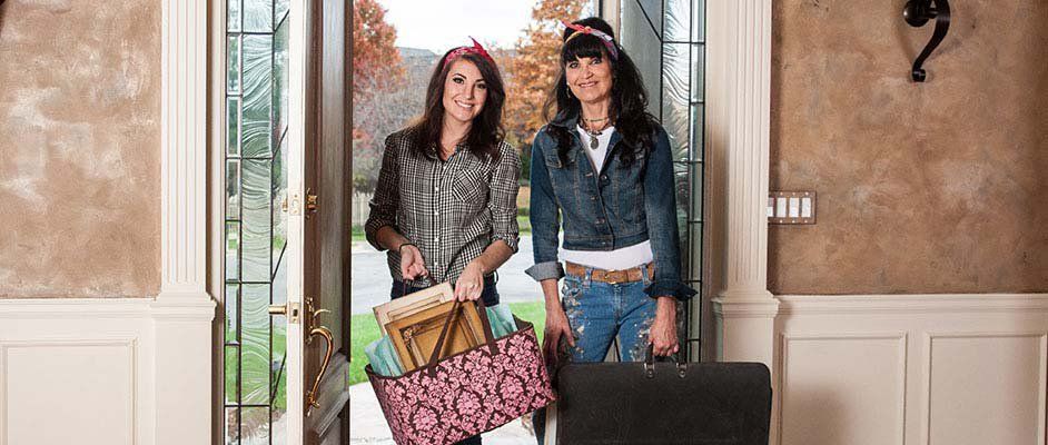 Two Woman In Door Carrying Bags