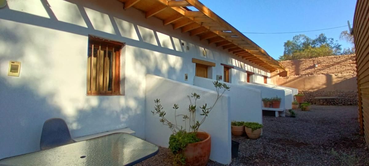 Un edificio blanco con techo de madera y una mesa delante de él.