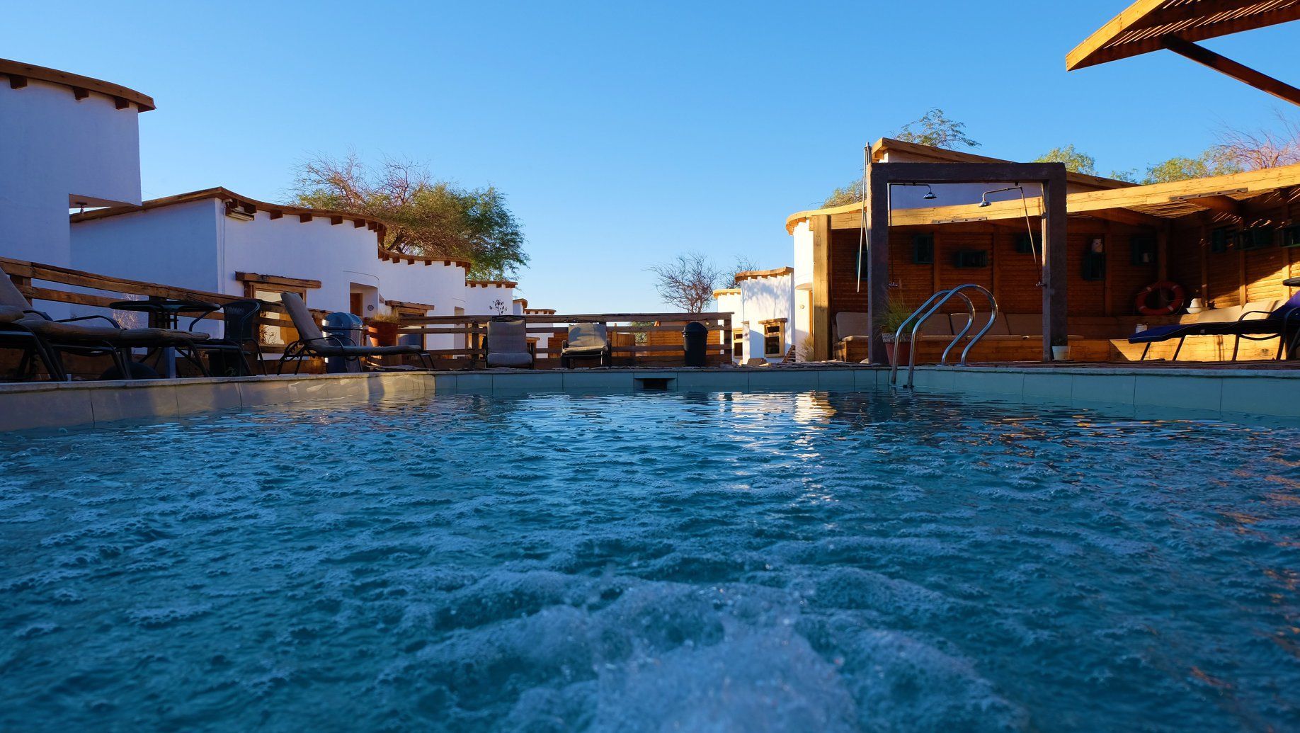 Una gran piscina rodeada de edificios y sillas en un día soleado.