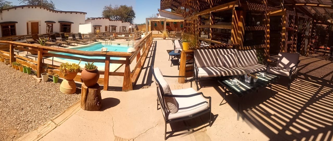 Un patio con sillas y una piscina al fondo.