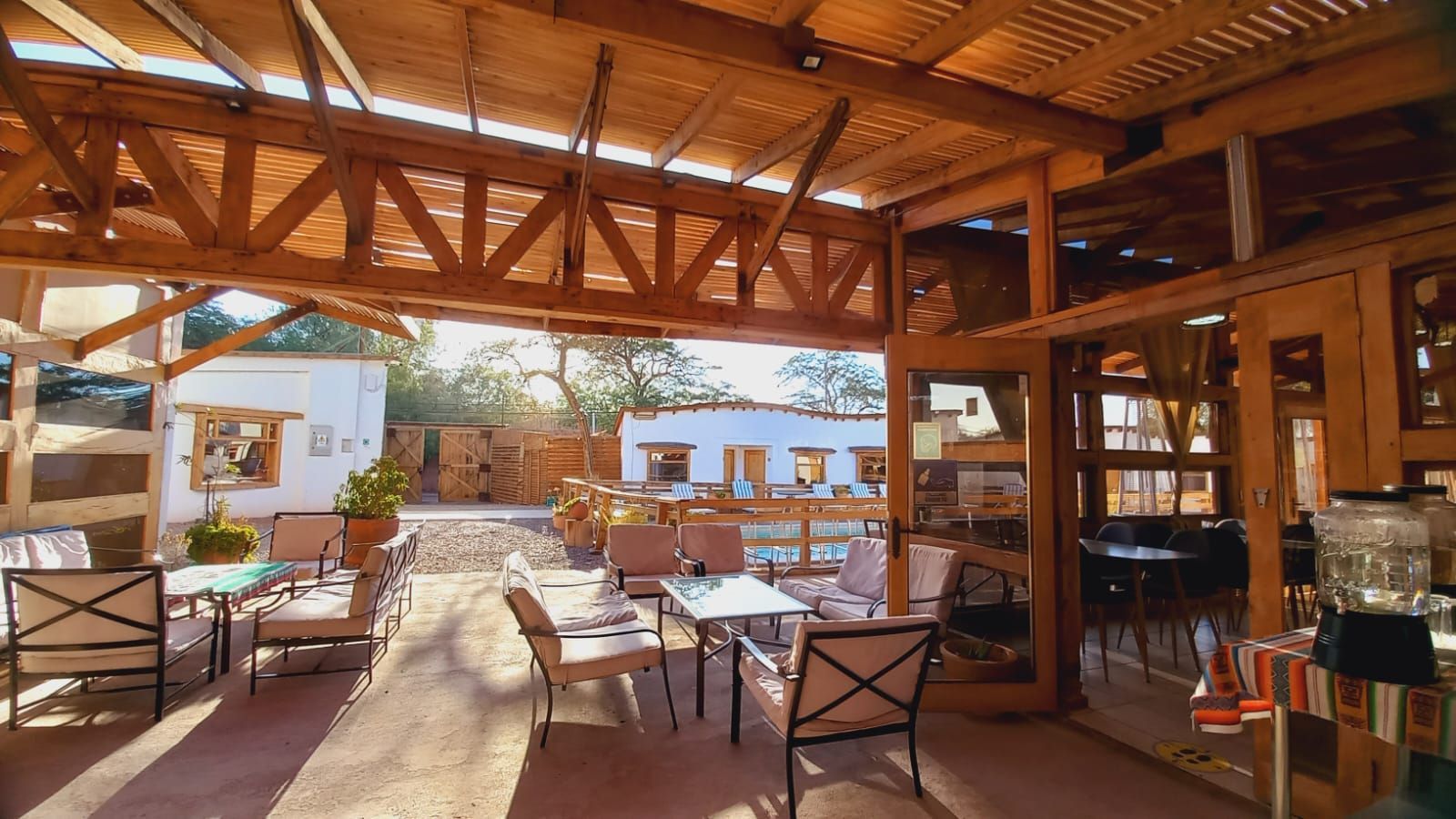 Un patio con mesas y sillas bajo un techo de madera.