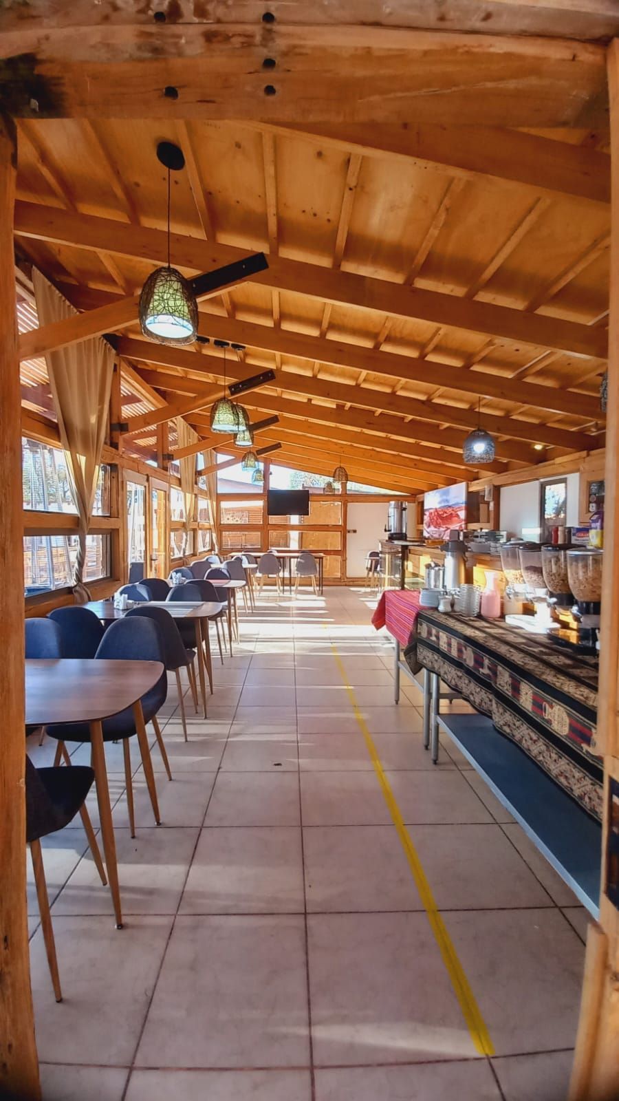 Un restaurante con mesas y sillas bajo un techo de madera.