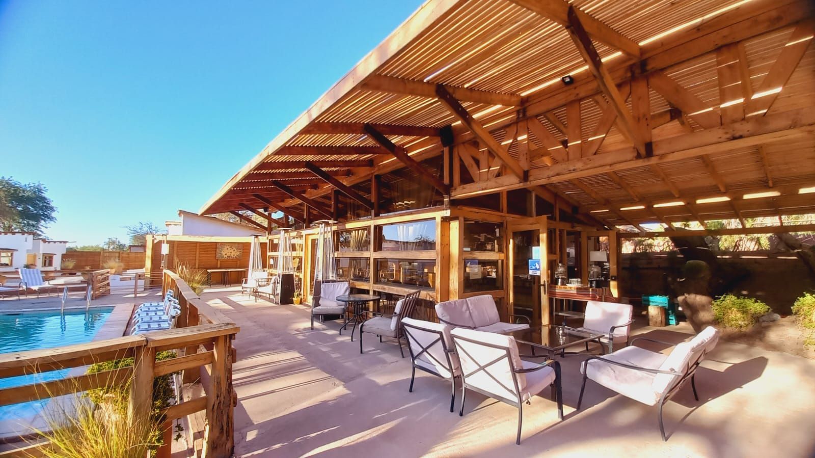 Un patio con sillas y una piscina al fondo.