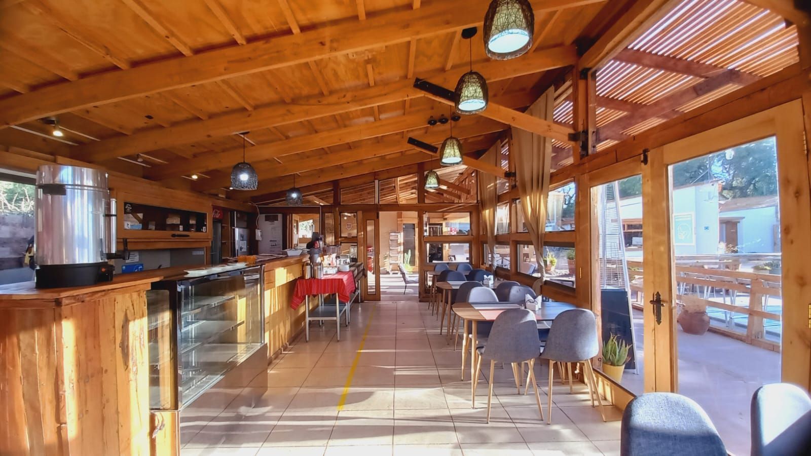 Un restaurante con mesas y sillas bajo un techo de madera.