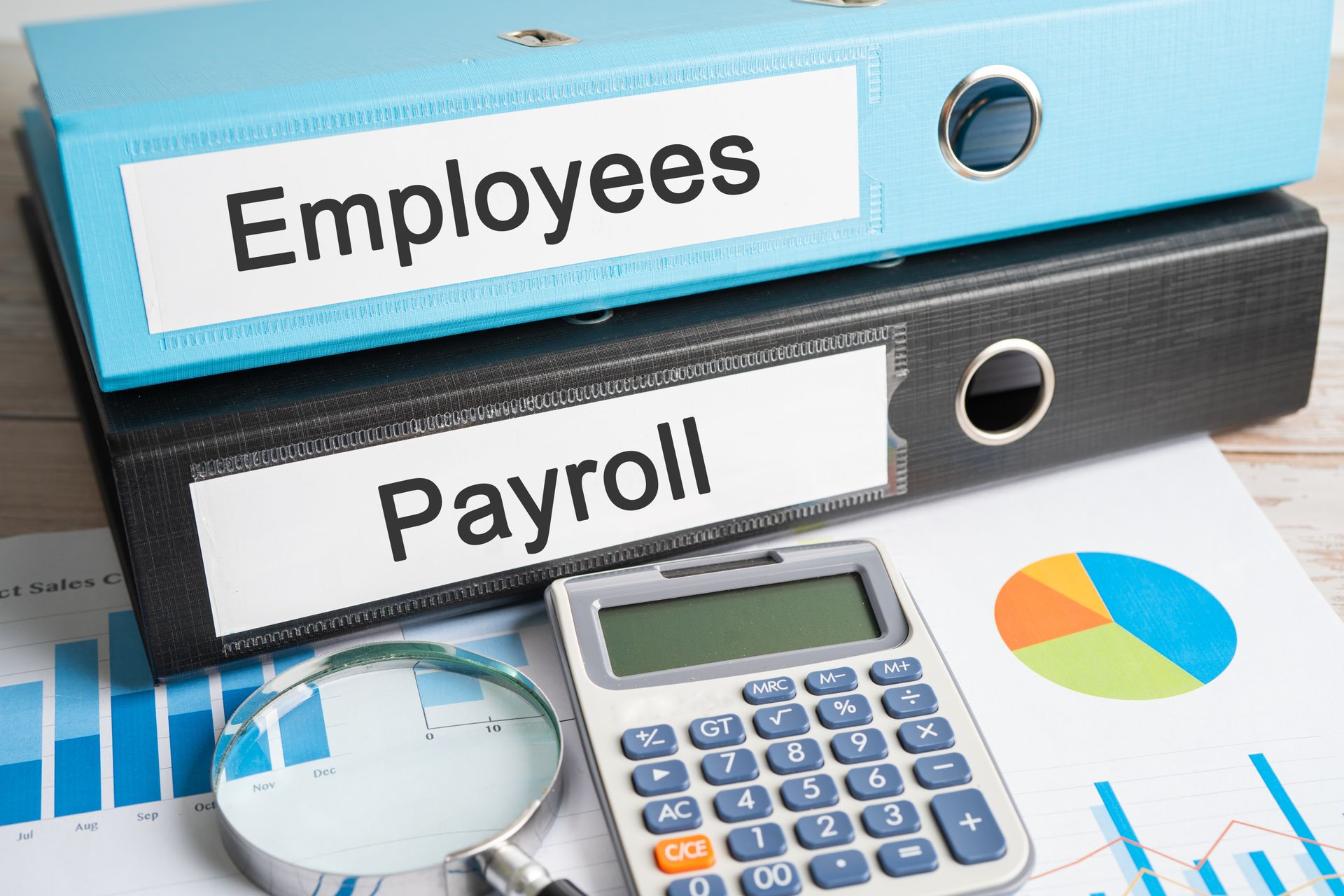 Employees and payroll folders beside a calculator and financial charts