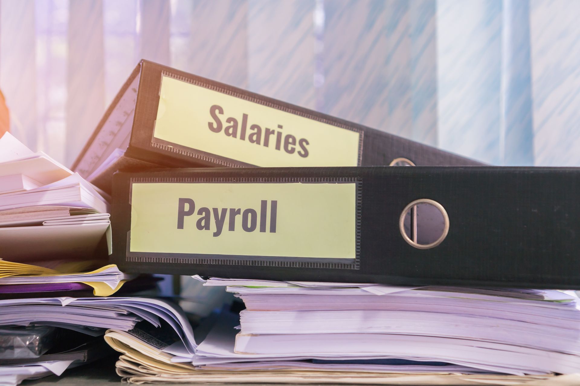 Payroll and salaries binders stacked on papers in an office setting