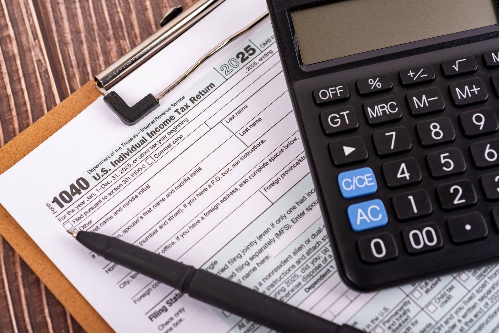 Calculator on tax forms with a pen and clipboard on a desk