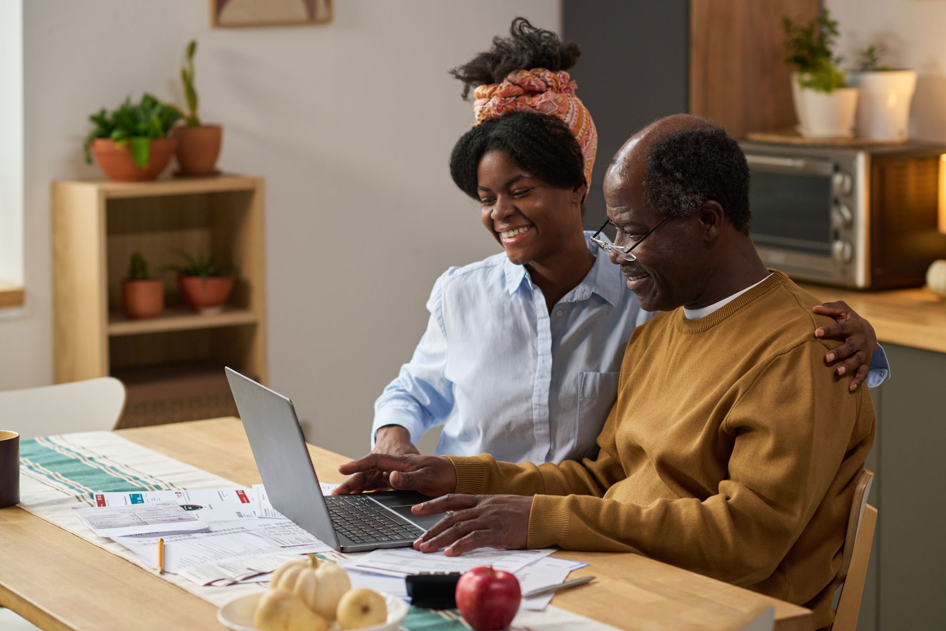 Two people sitting on the floor reviewing bills and paperwork beside a couch