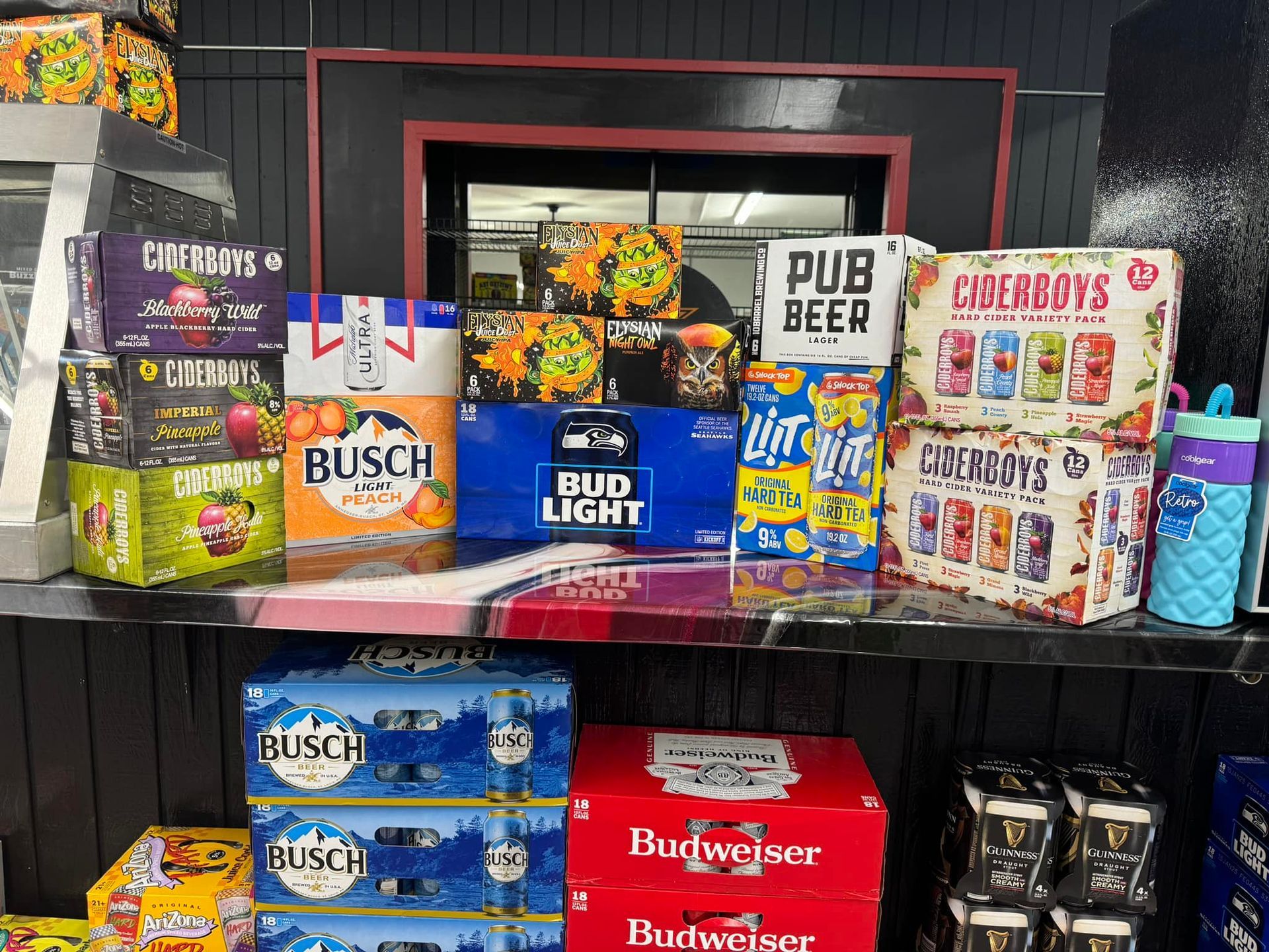 A shelf filled with boxes of beer including bud light and budweiser.