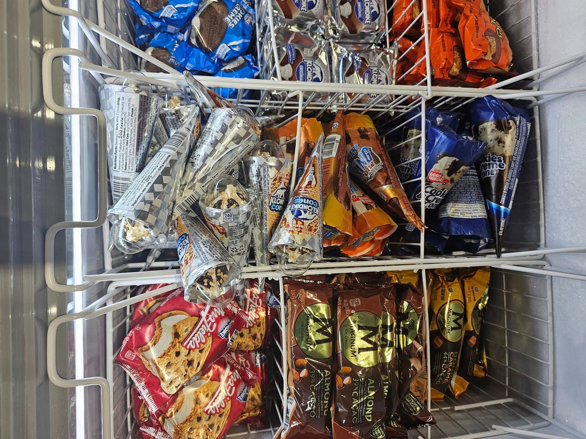 A freezer filled with a variety of ice cream cones.