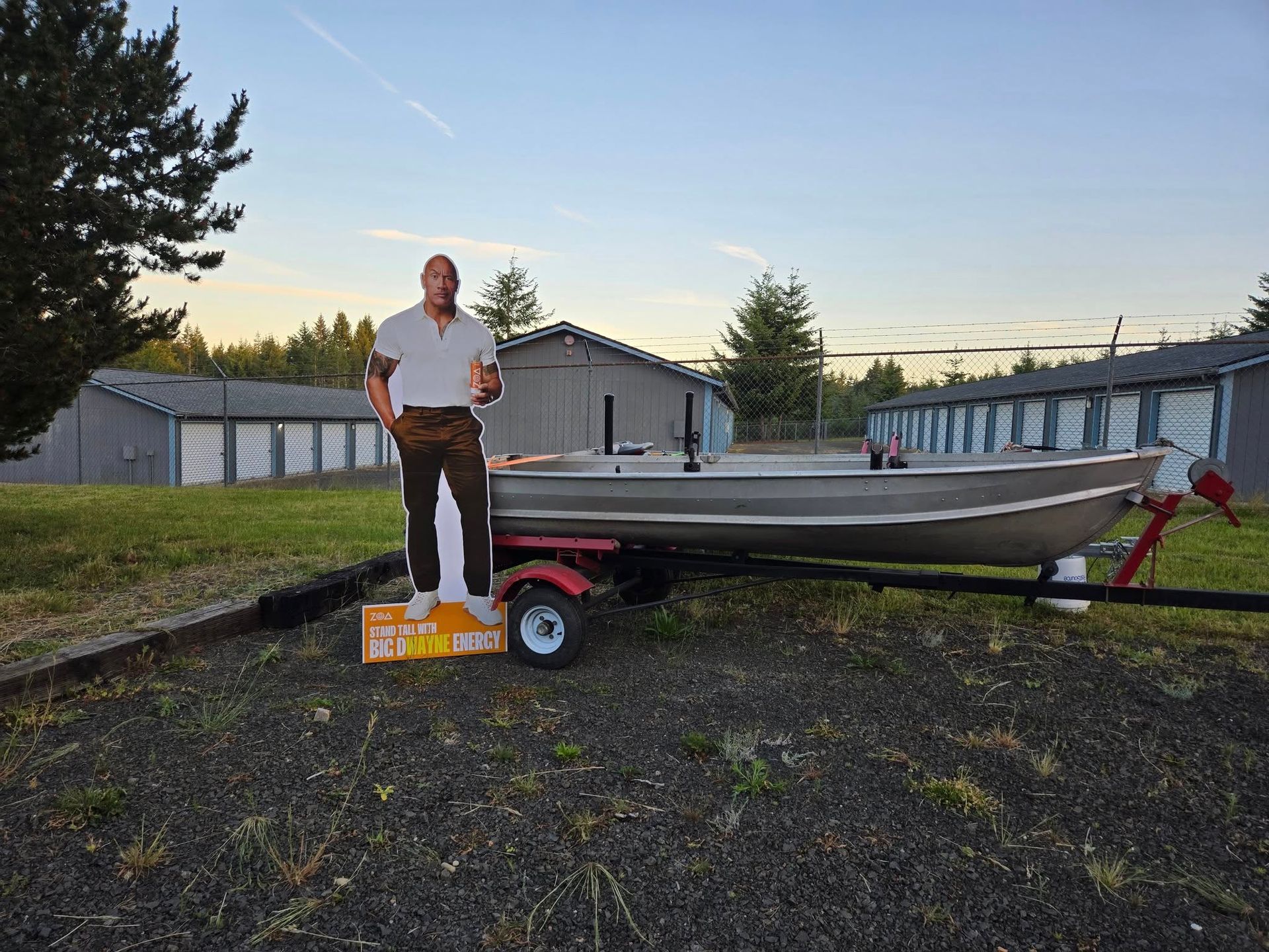 A man is standing next to a boat on a trailer.