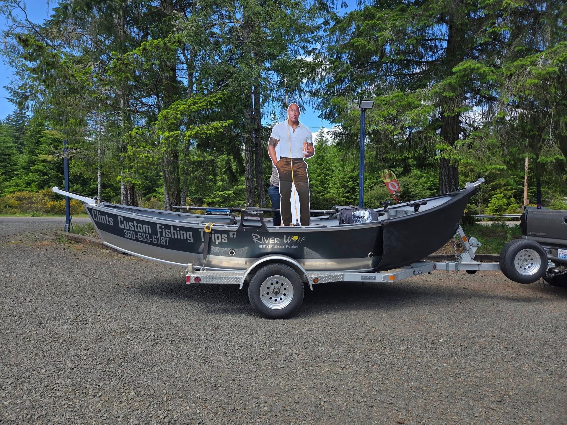 A man is standing on top of a boat on a trailer.