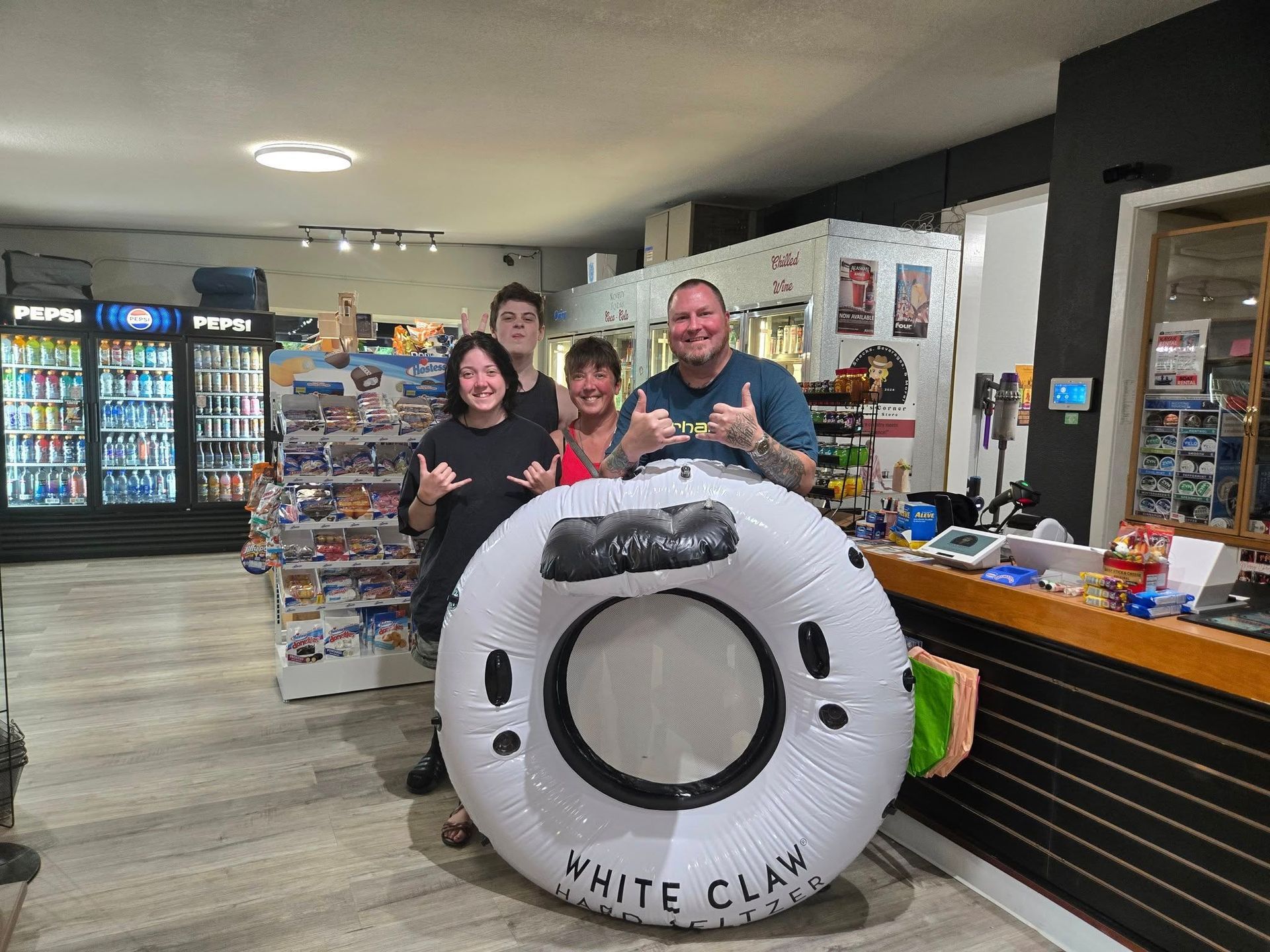 A group of people are posing for a picture with a white claw tube in a store.