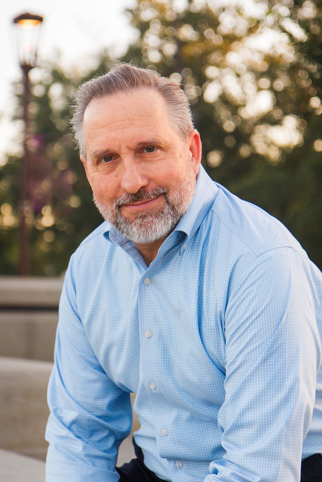 A man in a suit and blue shirt is smiling for the camera.