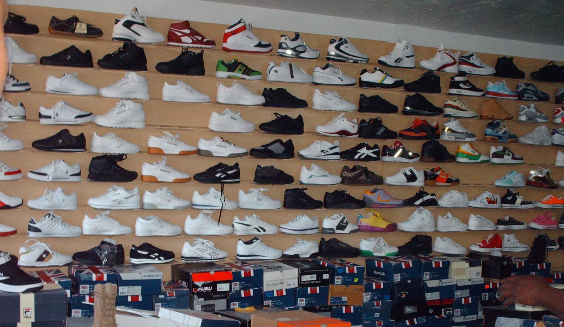 Wall display of various sneakers in boxes and on shelves.