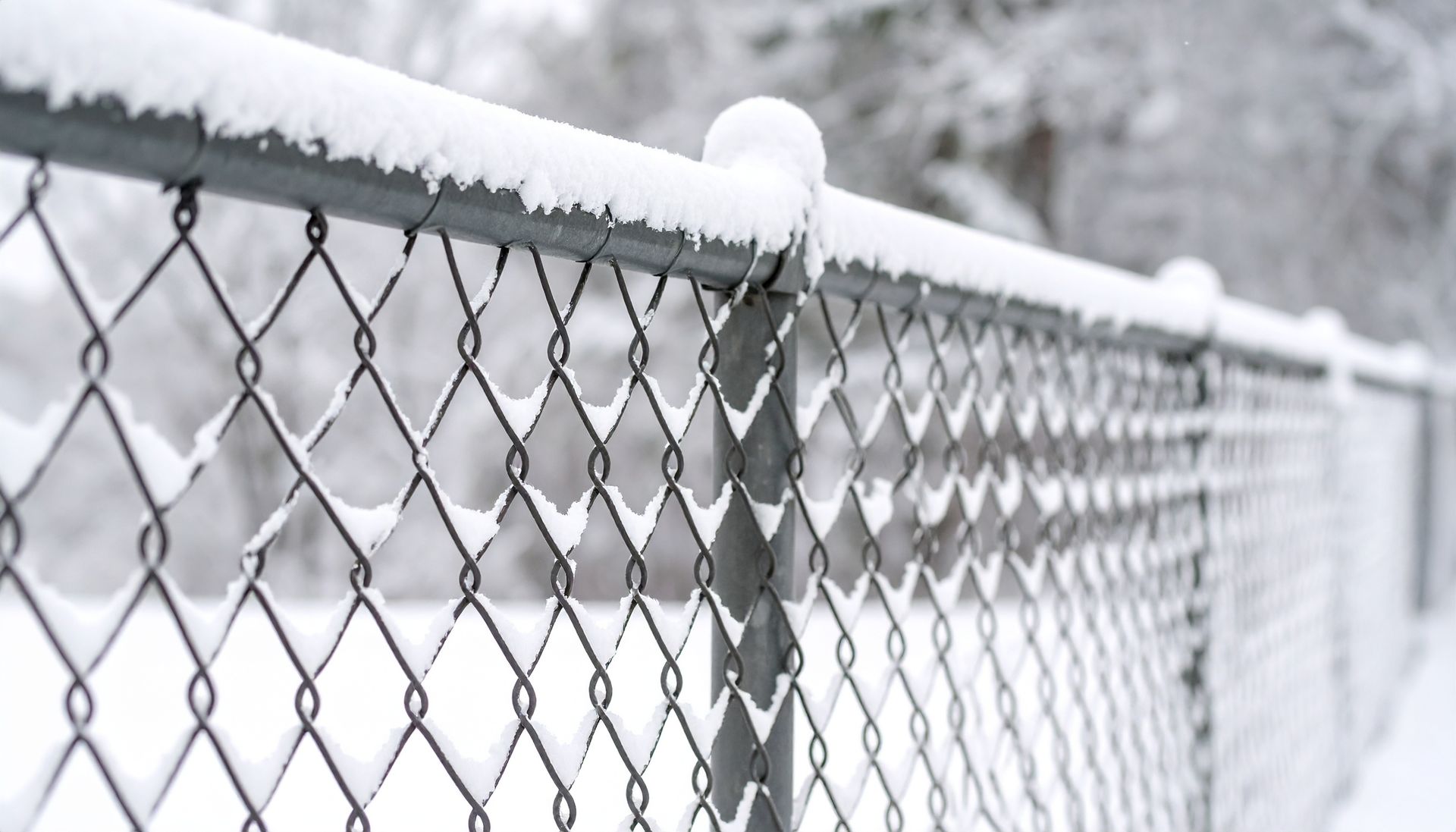 A chain link fence is covered in snow.