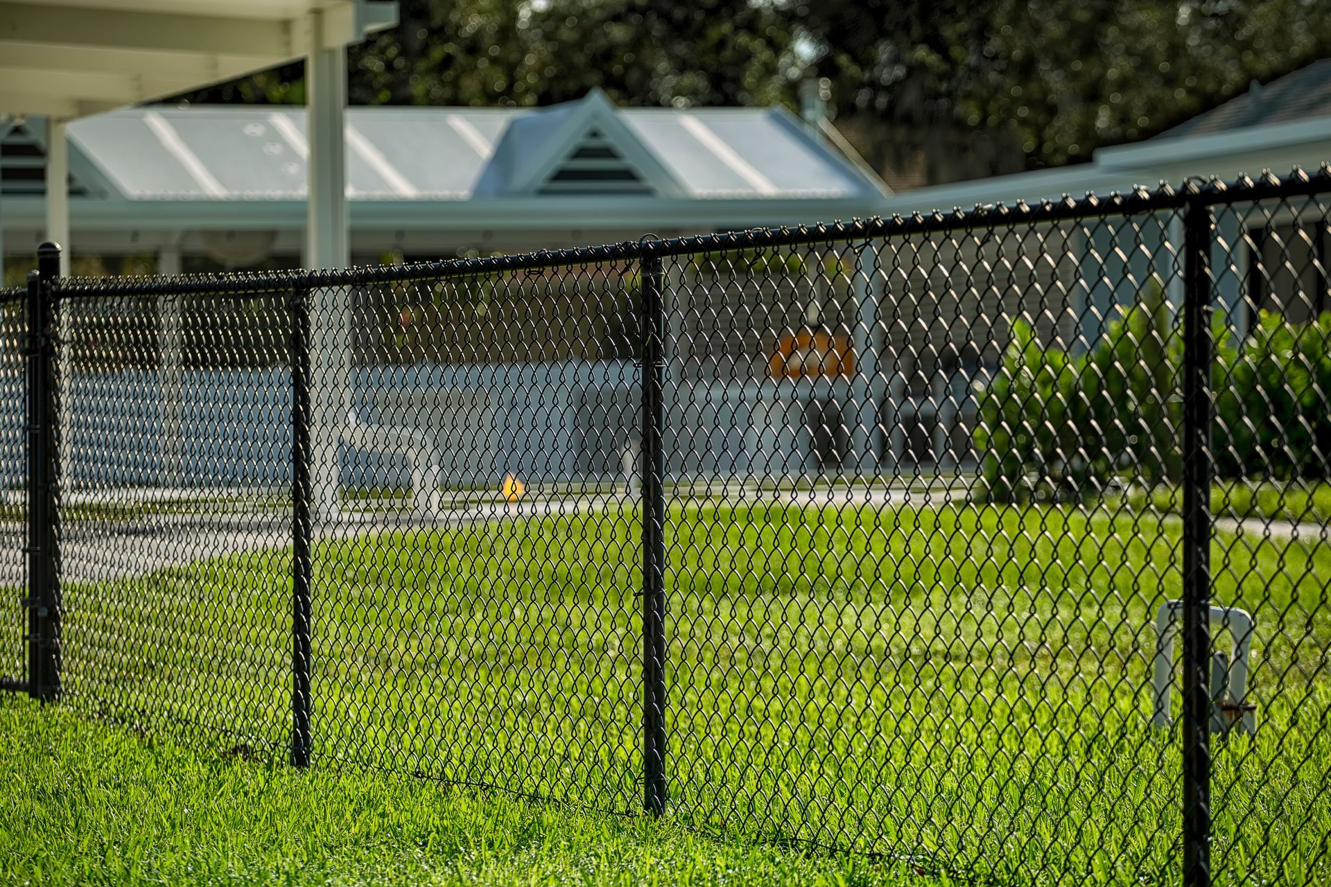 A white lattice fence is surrounded by snow in front of a house.