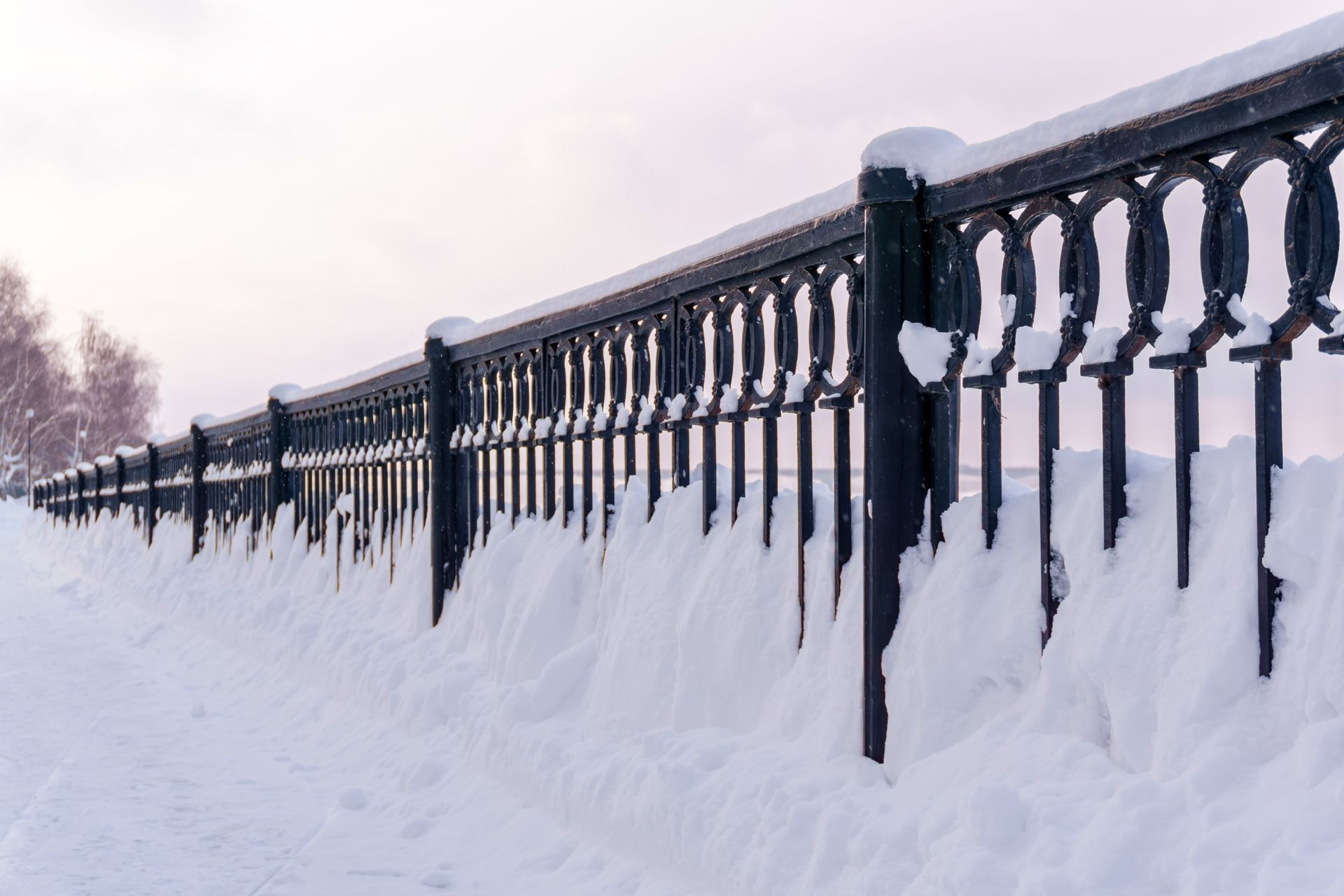 A fence is covered in snow on a snowy day.