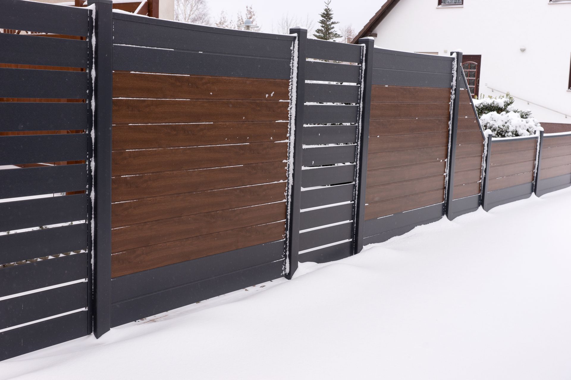Dark brown and gray modern fence in snowy setting.