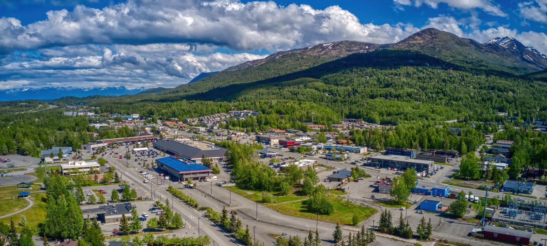 Anchorage, Alaska skyline with snow-capped mountains in the background and water in the foreground.