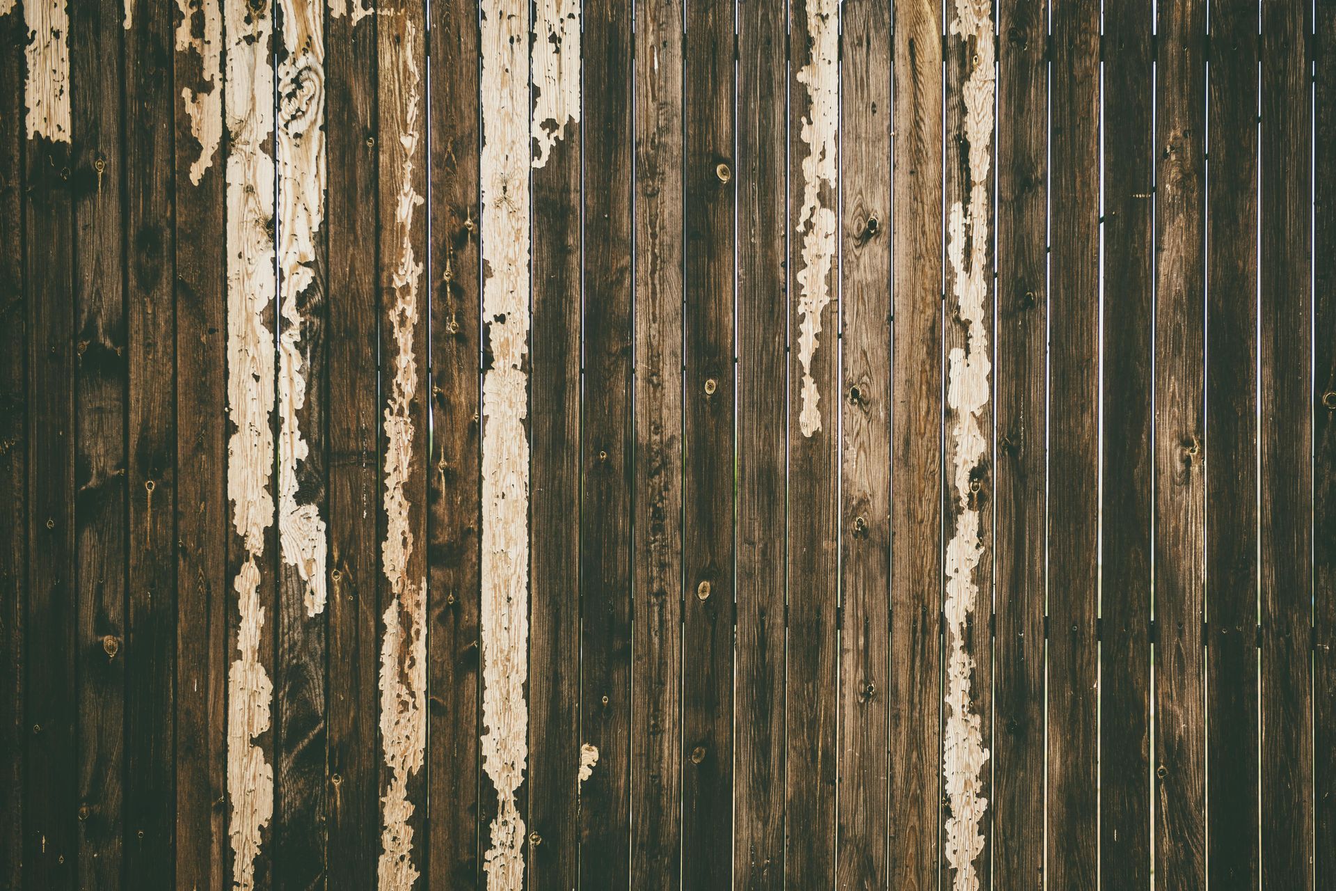 A close up of a wooden fence with white paint peeling off of it.
