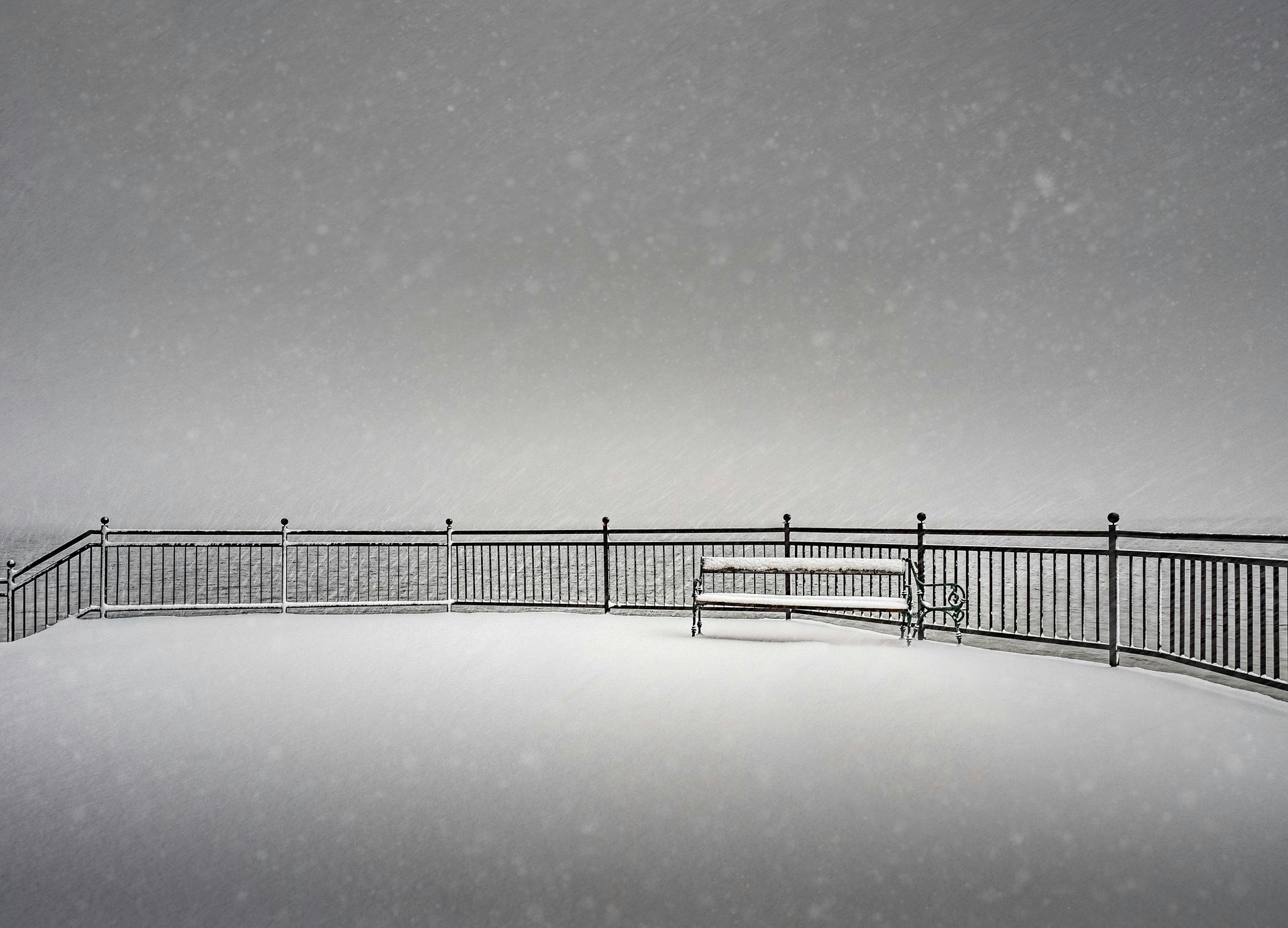 A black and white photo of a fence covered in snow.