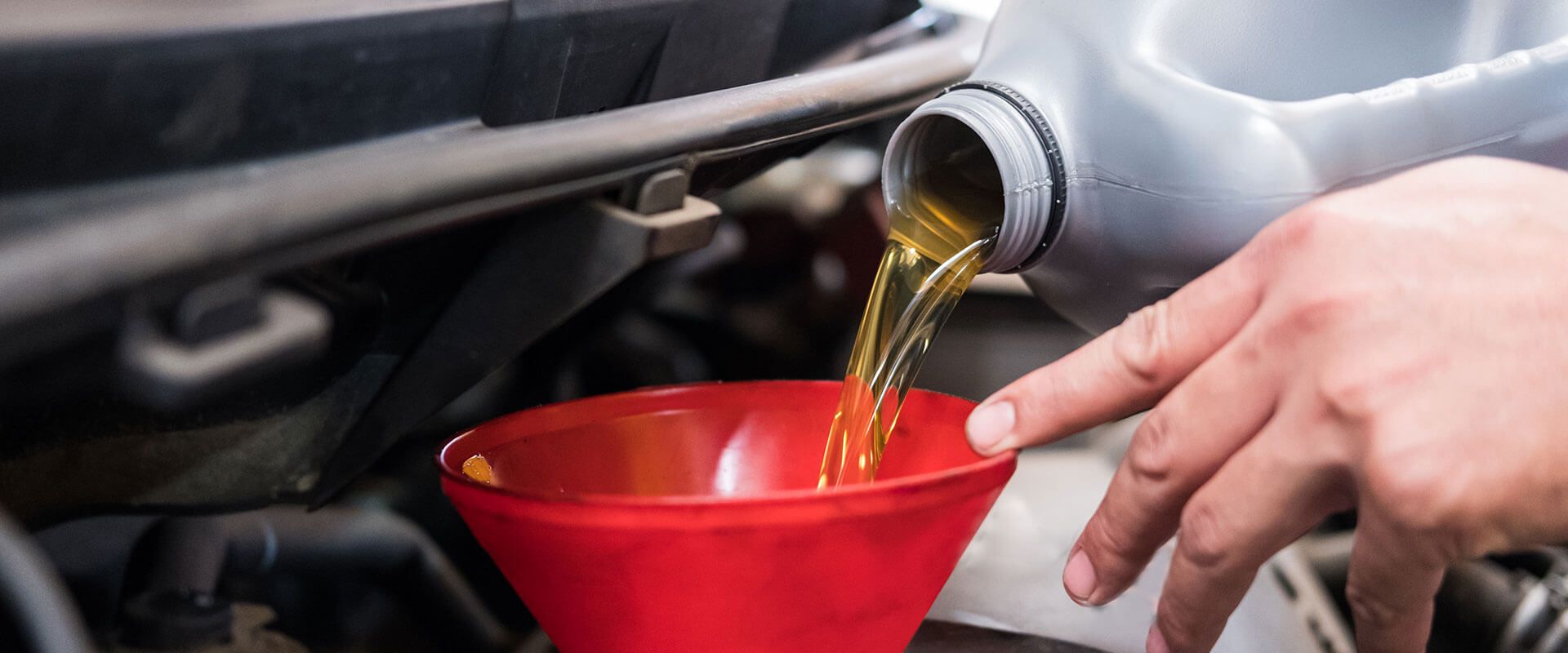 pouring oil into an oil funnel into an engine