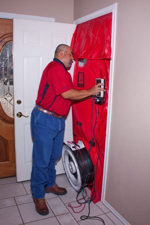 A man is standing in front of a door with a fan attached to it.