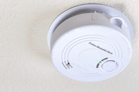 A white smoke detector is sitting on a white wall.