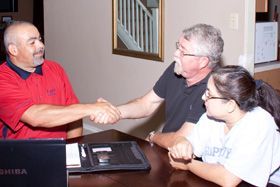 A man and a woman are shaking hands while sitting at a table.