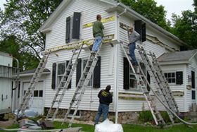 A group of men are working on the side of a house.