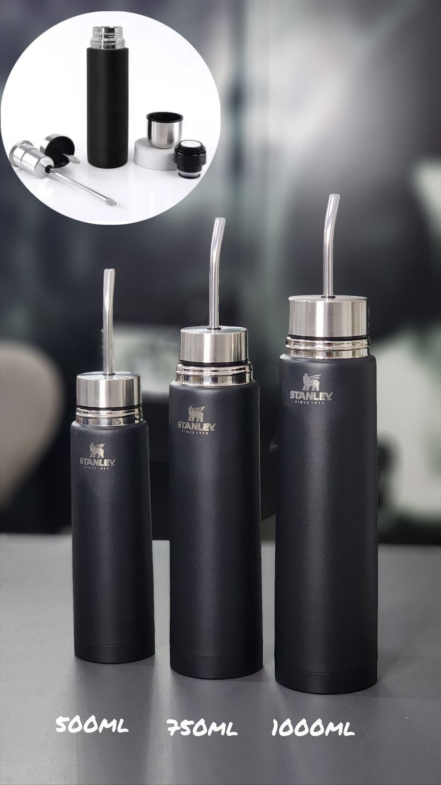 Botella térmica Stanley de color rosa con tapa plateada y tapón negro independiente, sobre superficie reflectante.