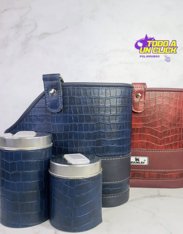 Contenedores de cuero azul y burdeos. Dos botes con tapas plateadas y dos recipientes más grandes y altos. Fondo de mármol.