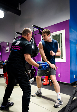 Two men are boxing in a gym with purple walls.