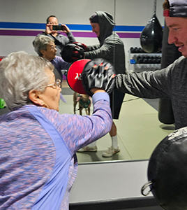 A man and woman are boxing in front of a mirror.