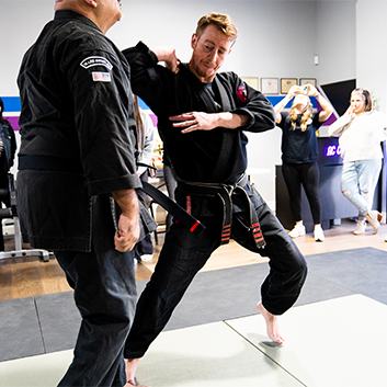 Two men are practicing martial arts in a gym.