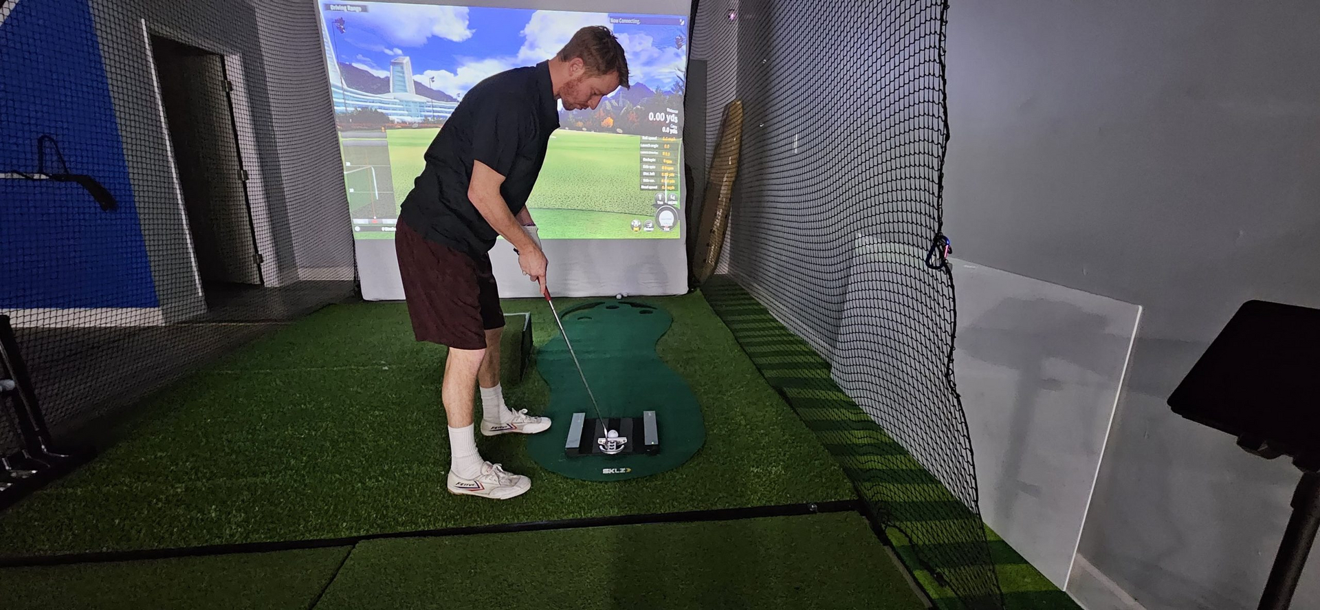 A man is playing golf in a simulator.