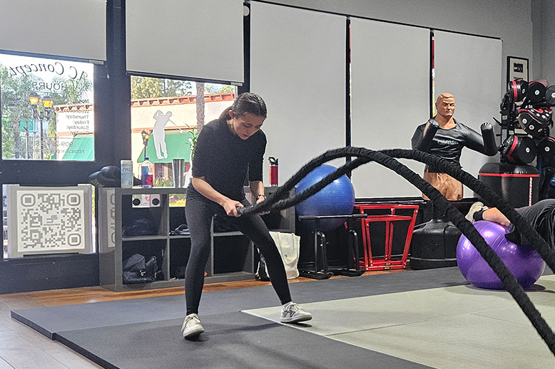 A woman is holding a rope in a gym.