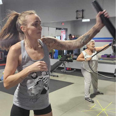 A woman with a tattoo on her arm is holding a stick in a gym