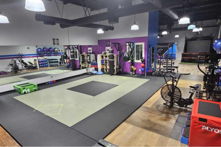 A gym with a lot of exercise equipment and a purple wall.