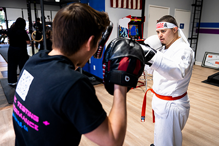 Two men are practicing martial arts in a gym.