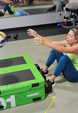 A woman is sitting on the floor in front of a green box with the number 1 on it