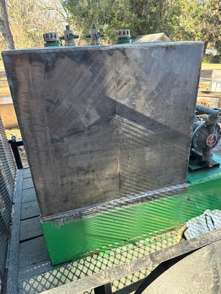 Large, dark, rectangular tank with green accents and a pump, outdoors.