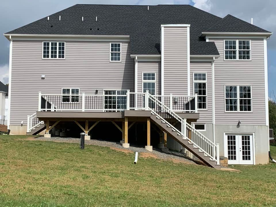 The back of a large house with a large deck and stairs.