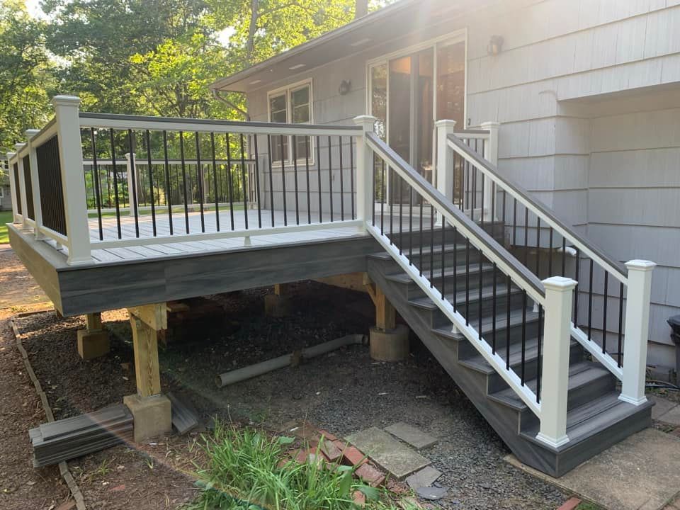 A deck with stairs leading up to it is in front of a house.