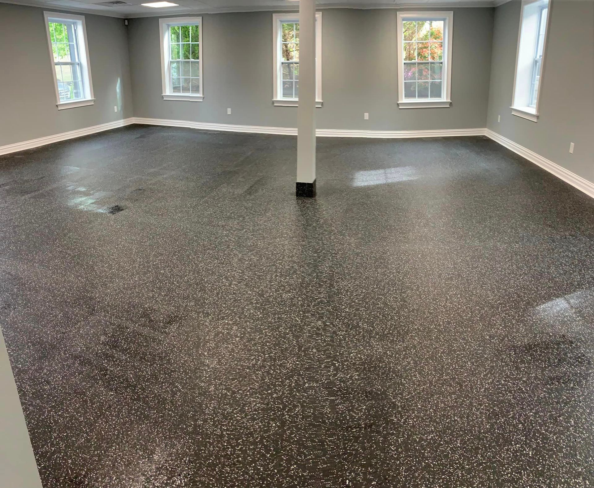 A large room with a black floor and a pillar in the middle.