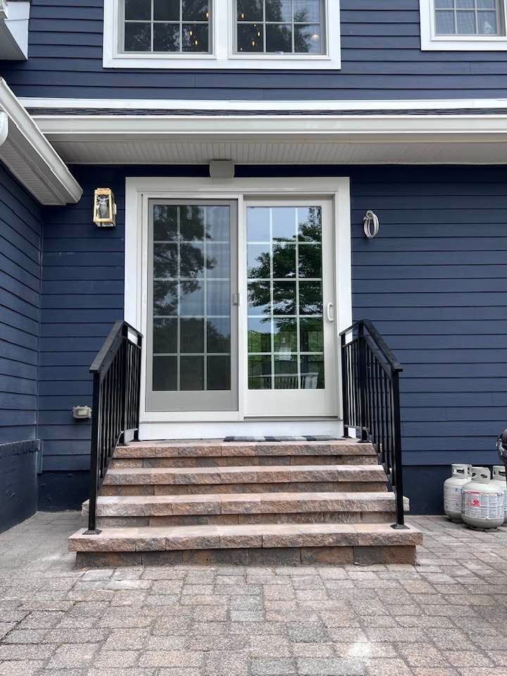 A blue house with a sliding glass door and stairs