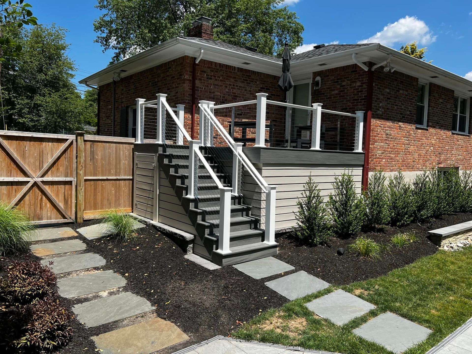 A brick house with a deck and stairs leading up to it.